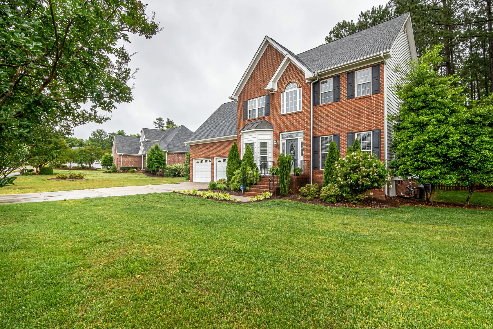 A brick house with a freshly mulched bed and a mown lawn